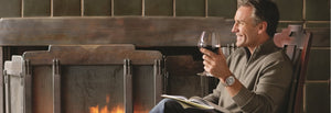 Guest enjoying a glass of wine by the fireplace while reading a book at The Lodge at Torrey Pines